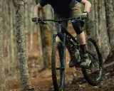 Rowerzysta w kasku i ochraniaczach pokonuje leśny szlak na rowerze górskim, jednym z wielu rodzajów rowerów do jazdy terenowej.