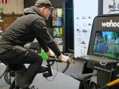 Mężczyzna na rowerze stacjonarnym, który jest częścią trenażera MTB, ściga się wirtualnie.