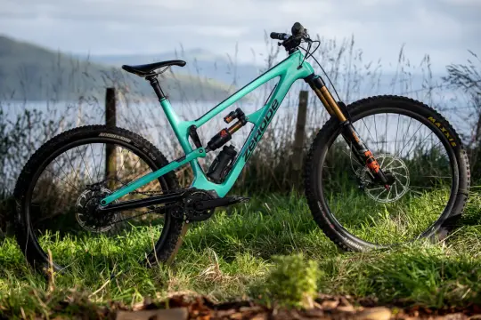 Turkusowy rower full-suspension marki Zerode, gotowy na górskie trasy. Wśród wielu marek rowerów, ten wyróżnia się designem.