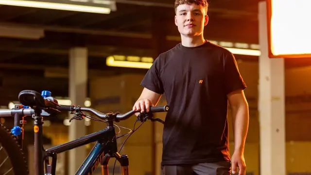 Młody mężczyzna z rowerem, gotowy na wyzwanie 100 km na rowerze.