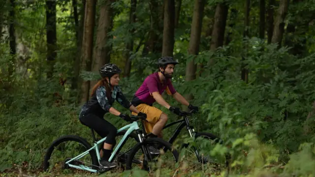 Para jadąca na rowerach górskich (MTB) przez las. Czy to szlak gravelowy czy terenowy?