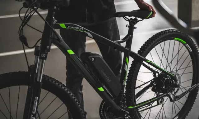 Czarny rower elektryczny z zielonymi akcentami i baterią Green Cell. Dowiedz się, jak sprawdzić baterię w rowerze elektrycznym.