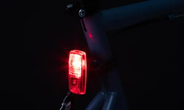 Czerwone światło tylne roweru elektrycznego świeci, pokazując, jak włączyć światła w rowerze elektrycznym.