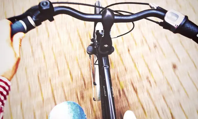 Widok z perspektywy rowerzysty. Dłoń trzyma kierownicę, a przed nami rozmyte tło. Jak podnieść kierownicę w rowerze?