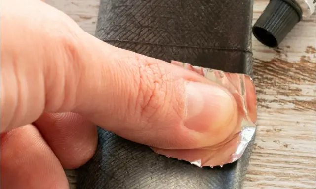 Palec dociska łatkę do dętki rowerowej, pokazując, jak wymienić dętkę w rowerze.