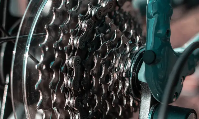 Zbliżenie na kasetę zębatek rowerowych i mocowanie przerzutki tylnej. Metalowe zębatki i łańcuch tworzą skomplikowany mechanizm.