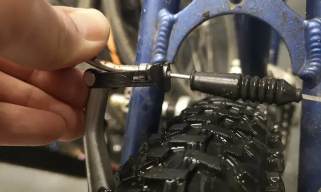 Dłoń reguluje linkę hamulca v-brake, by wyeliminować piszczące hamulce w rowerze.