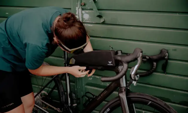 Osoba montuje torbę podsiodłową do roweru. Przygotowania do składania roweru przed wyprawą.