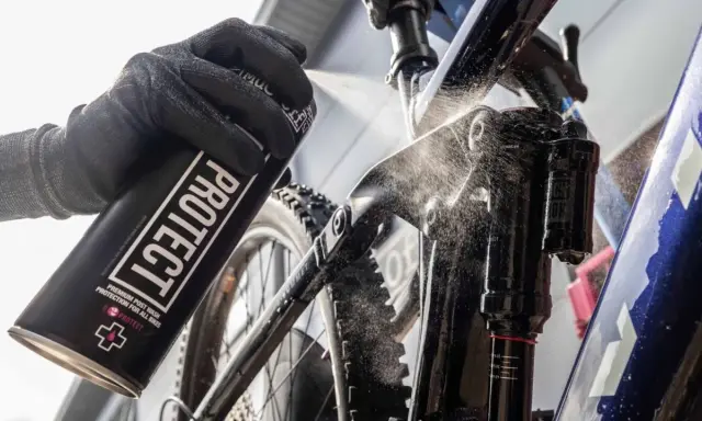 Rękawica z puszką "PROTECT" rozpyla środek na ramę roweru elektrycznego, pokazując, jak myć rower elektryczny.