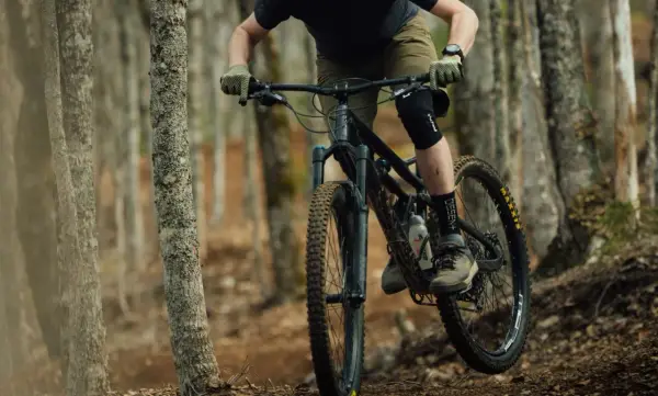 Rowerzysta w kasku i ochraniaczach pokonuje leśny szlak na rowerze górskim, jednym z wielu rodzajów rowerów do jazdy terenowej.