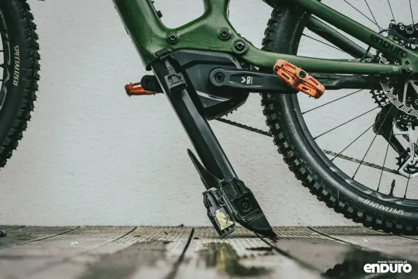 Zielony rower elektryczny z pomarańczowymi pedałami. Widoczny mechanizm, który ułatwia zrozumienie, jak wyjąć baterię z roweru elektrycznego.