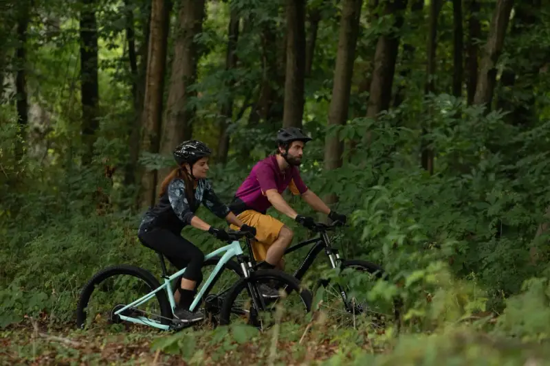 Para jadąca na rowerach górskich (MTB) przez las. Czy to szlak gravelowy czy terenowy?